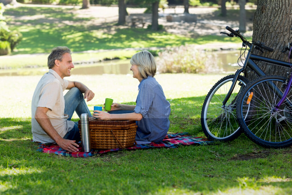 Couple having picnic outdoors, bikes leaning against tree.