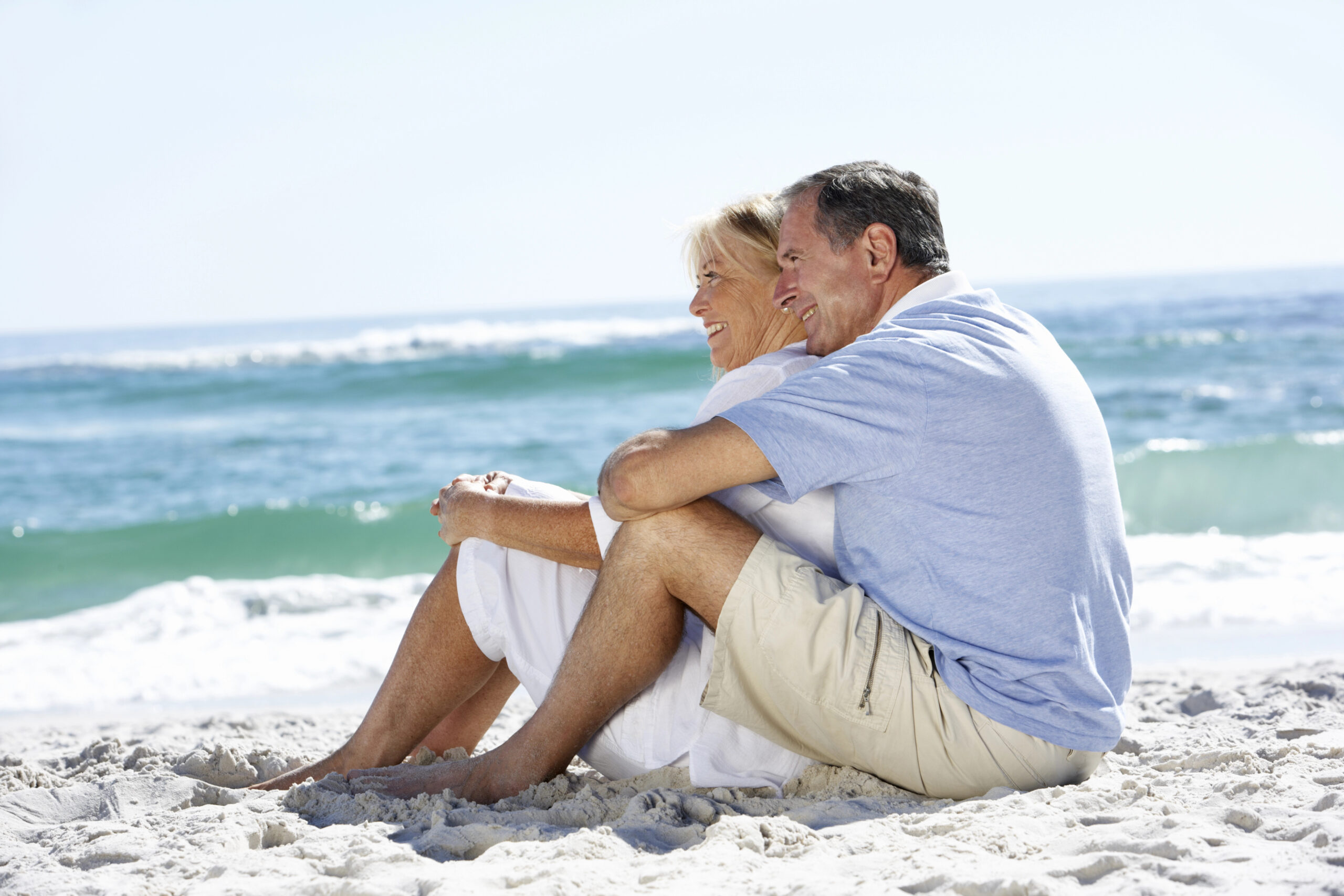 Older Retired Couple Sitting on Beach on Nice Sunny Day