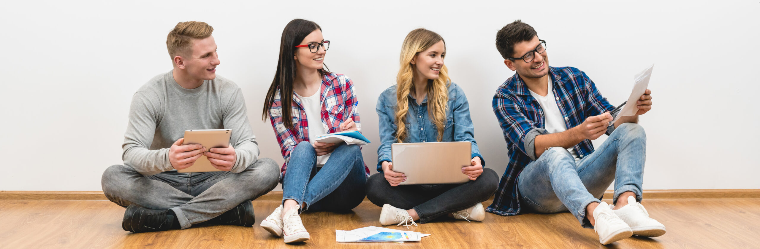 Young professionals sitting on the floor with their devices and spreadsheets.